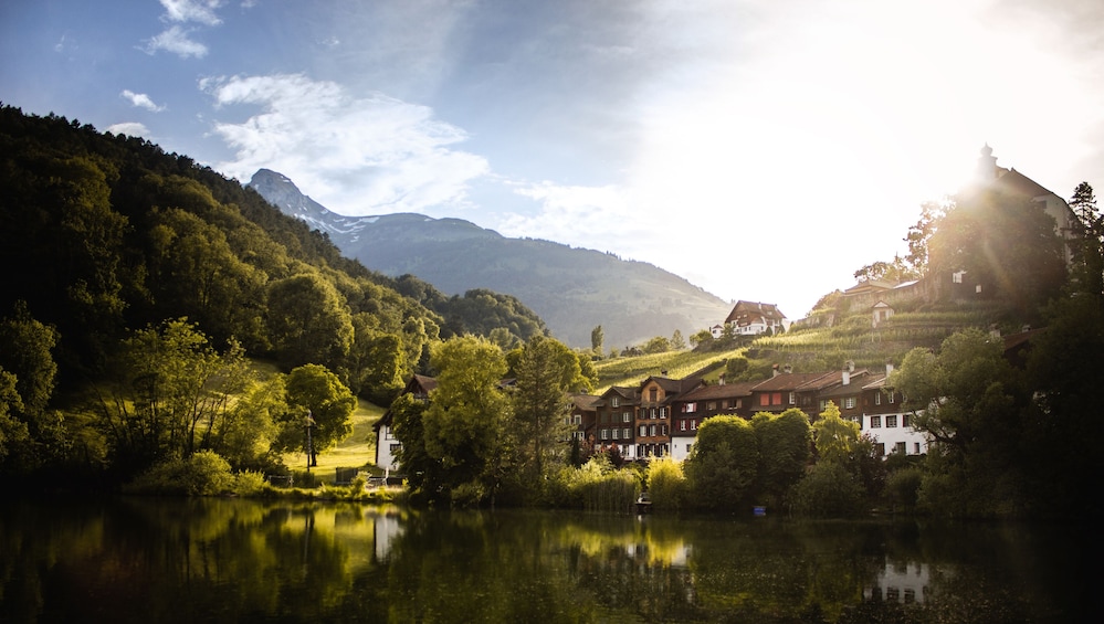 A serene lakeside village with traditional houses, lush greenery, and mountains in the background. 3