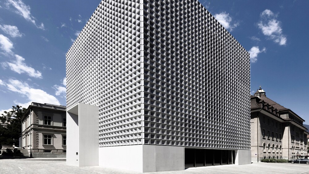 A modern skyscraper with a grid-like facade, surrounded by classical architecture. 1