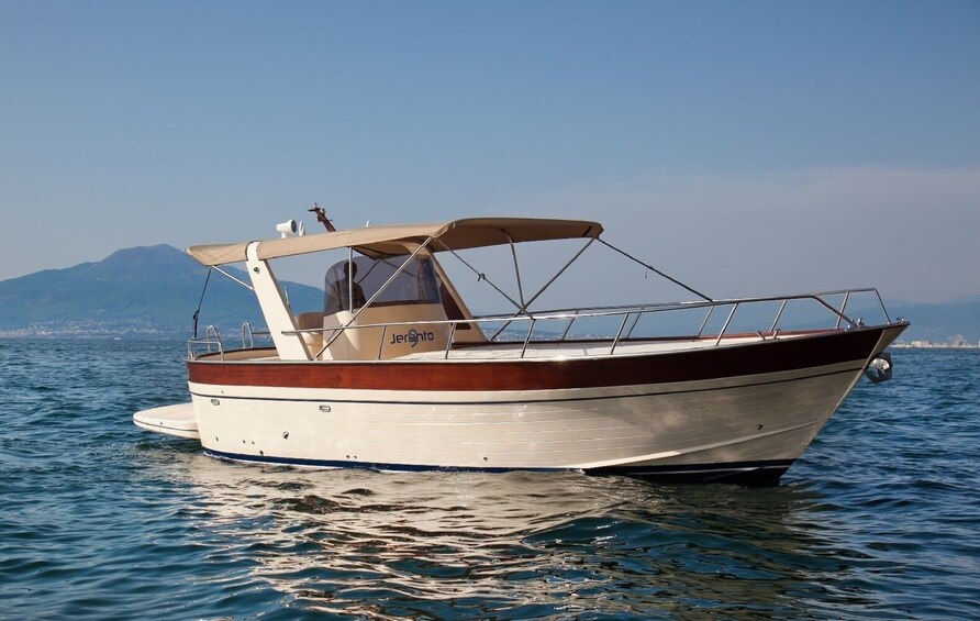 A boat named 'Jeronto' on calm water with a mountainous backdrop. 1
