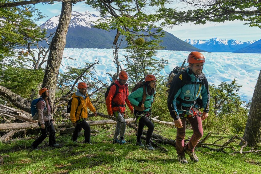 A group of hikers on a trail with a glacier and mountains in the background. 4