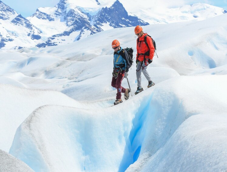 Two people hiking on a snowy mountain with a glacier in the background. 5