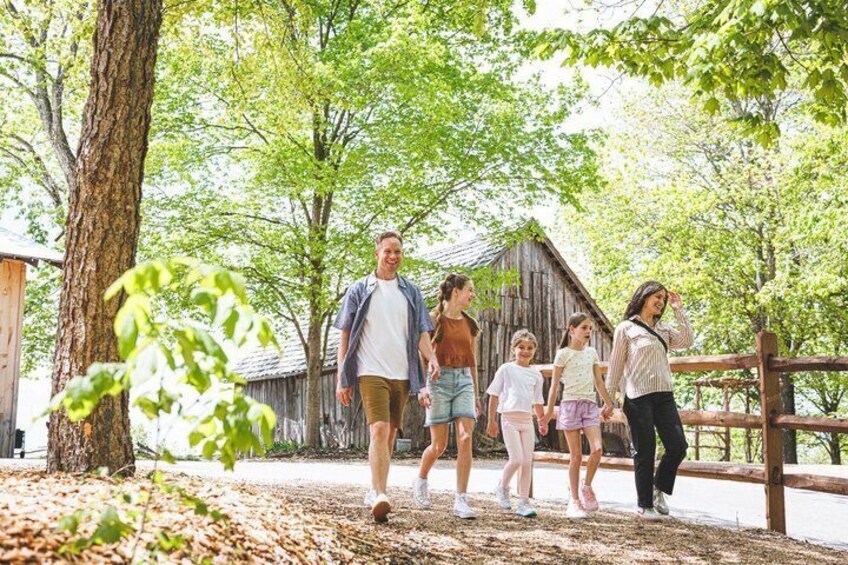 A family walking along a path with trees and a wooden fence in a park-like setting. 5