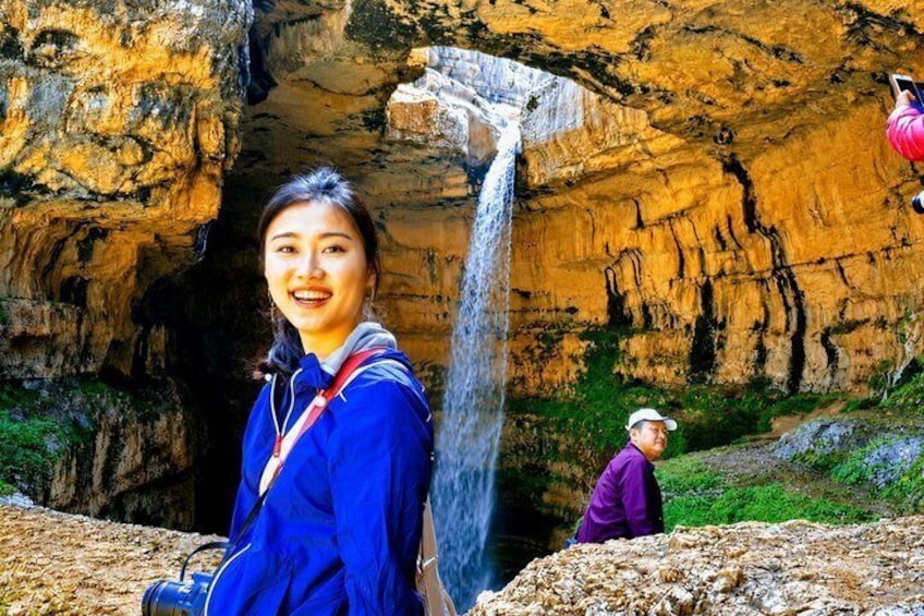 Una cascada dentro de una cueva, con una persona en primer plano y otra al fondo. 1