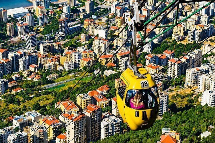 Un teleférico amarillo con el número 18, suspendido sobre una zona urbana densamente poblada con edificios de tejados rojos y vegetación. 5