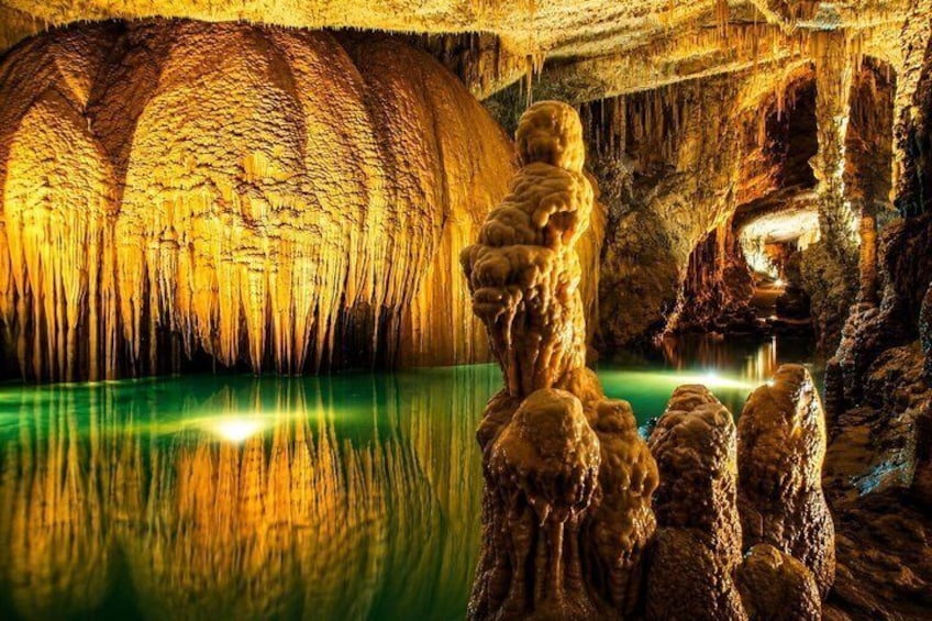 Una cueva con estalactitas y estalagmitas, un estanque reflectante y una fuente de luz. 2