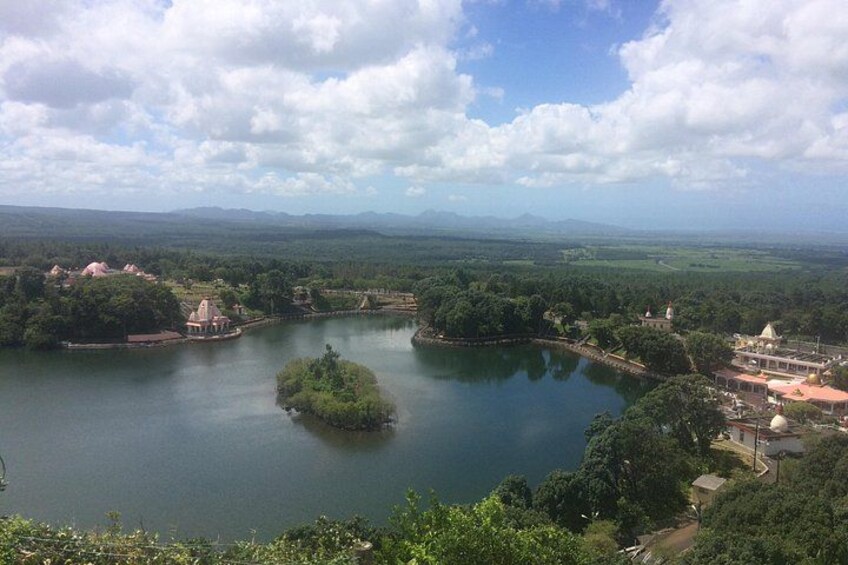 A lake surrounded by greenery, a temple, and distant mountains. 2