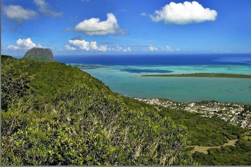 A coastal landscape with a mountain, clear blue waters, and a small settlement. 4