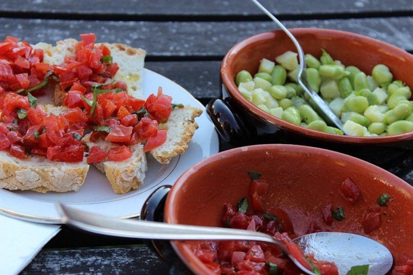A plate of bruschetta topped with diced tomatoes and basil, two bowls of green beans and diced tomatoes, and a spoon. 4