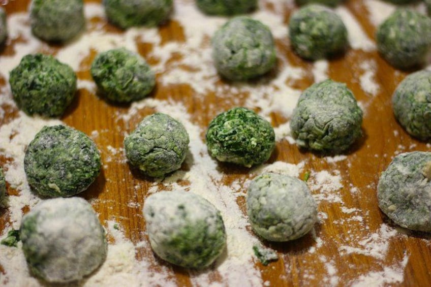 Several green, round food items on a wooden surface with flour scattered around. 3