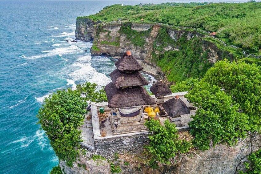 A cliffside with traditional thatched-roof structures, a rugged coastline, and lush greenery. 4