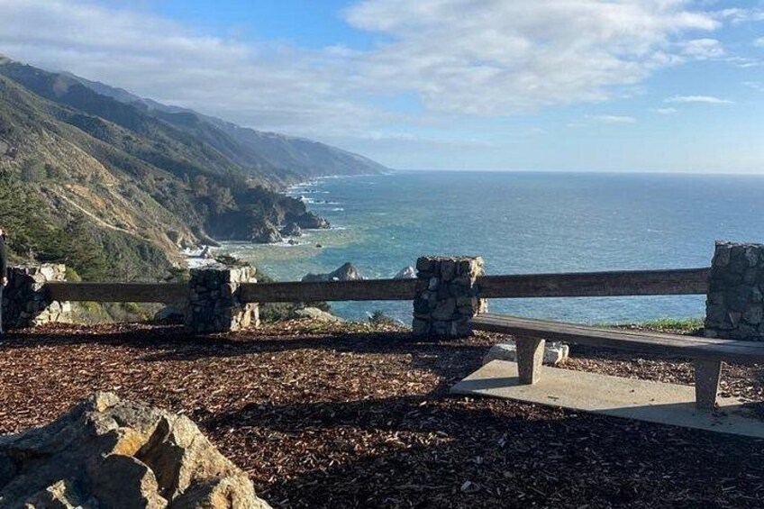 Een kustlandschap met een houten hek, rotsachtig terrein en uitzicht op de oceaan. 5