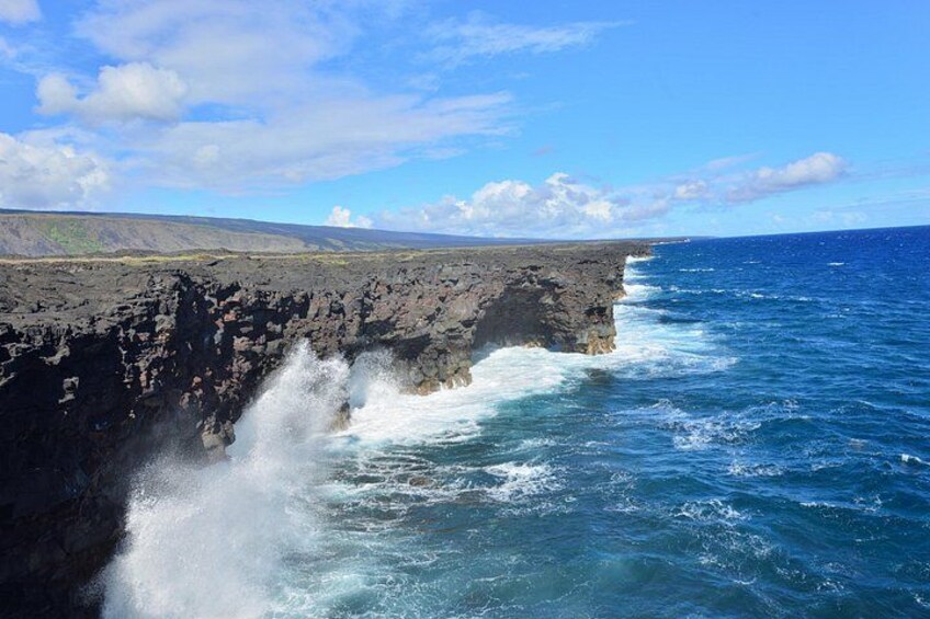 Un paysage côtier avec une falaise rocheuse et des vagues de l’océan qui s’y brisent. 1
