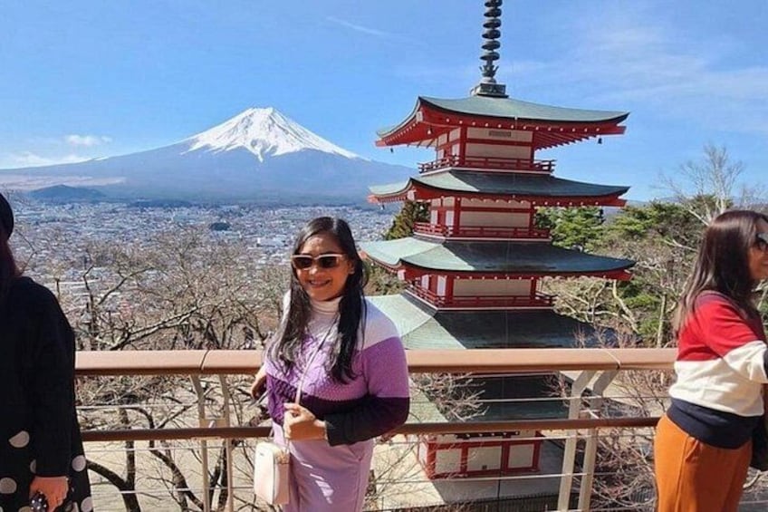 A person standing on a balcony overlooking a cityscape with a pagoda and Mount Fuji in the background. 3
