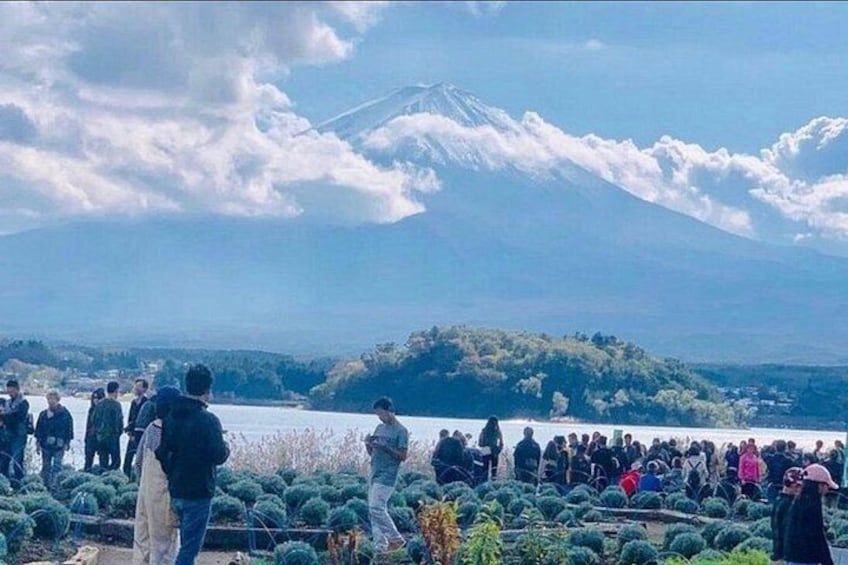 A group of people observing a mountain with a lake in the foreground. 4