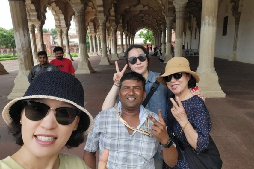 A group of people posing in a historical building with arches and columns. 1