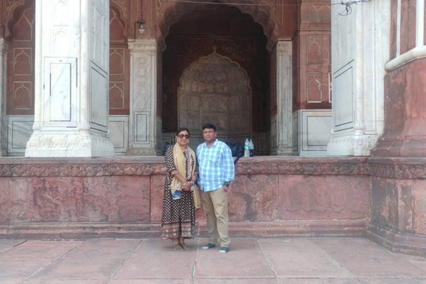 A couple standing in front of a historic building with ornate arches and columns. 5