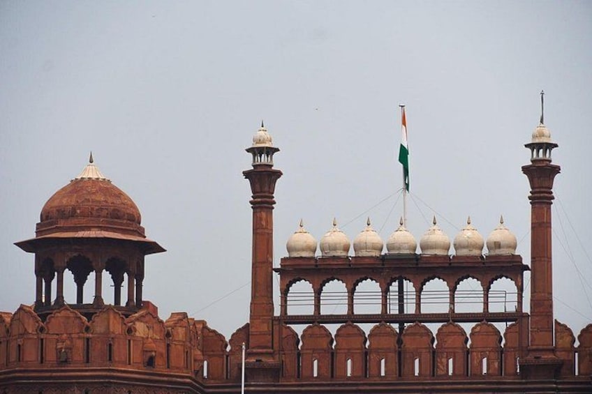 A historic building with domes and minarets, featuring a prominent flag. 3