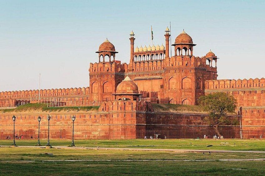 A large, historic building with multiple domes and towers, surrounded by a well-maintained lawn and a low wall. 1