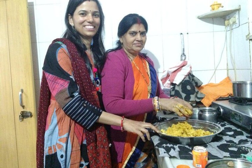 Two women cooking in a kitchen with a stove, a bowl of food, and a can of soda. 4