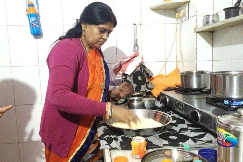 A person cooking in a kitchen with a stove, pots, and a bowl. 5