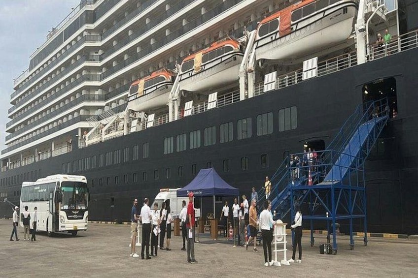 Ein großes Kreuzfahrtschiff liegt im Hafen, während Passagiere ein- und aussteigen. 5