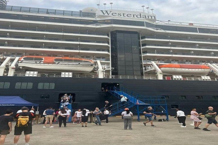 Ein Kreuzfahrtschiff liegt an einem Hafen, im Hintergrund ist ein großes Passagierterminal zu sehen. 4