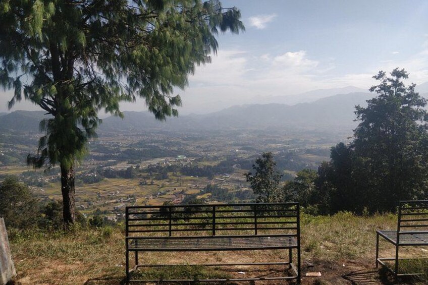 Un banco con vistas a un valle y montañas distantes. 1