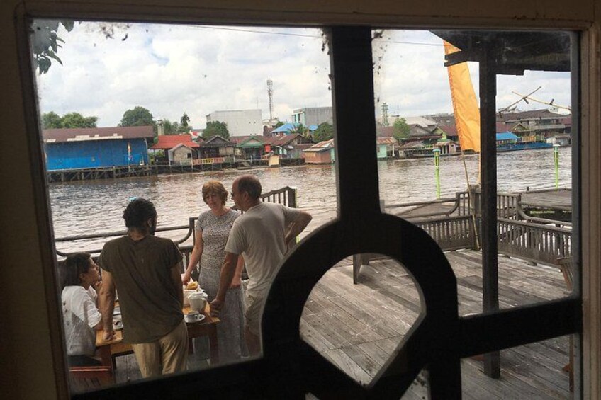 A group of people on a dock, a wooden pier, and buildings in the background. 2