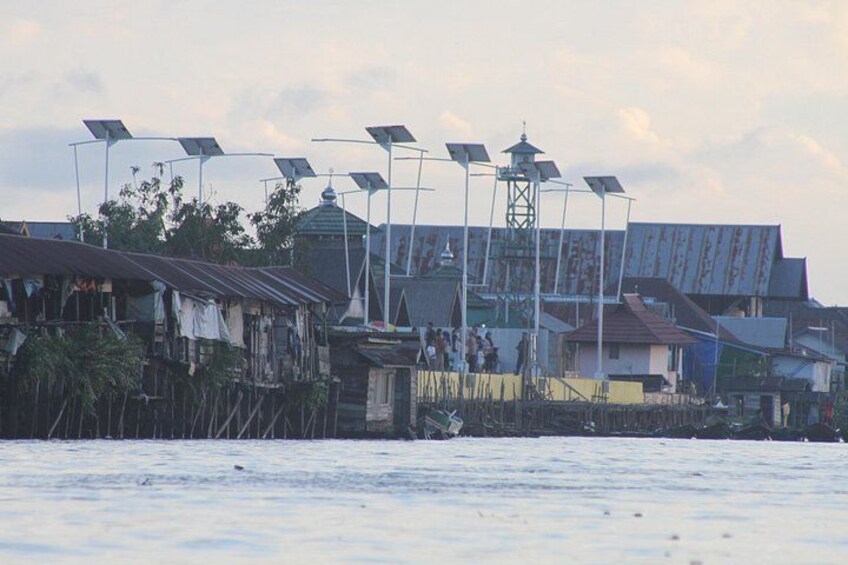 A coastal settlement with makeshift housing, solar street lamps, and a water body. 4