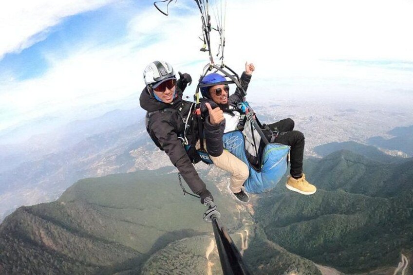 Two people skydiving with parachutes over a mountainous landscape. 3