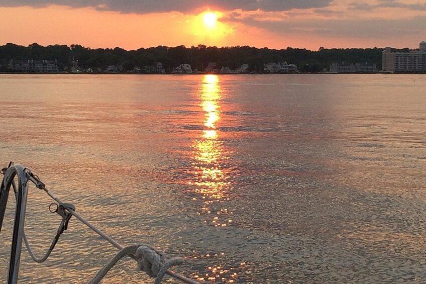 A sunset over a calm body of water with a boat in the foreground. 2