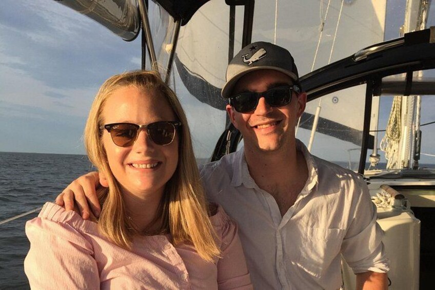 Two people on a sailboat with the ocean in the background. 4