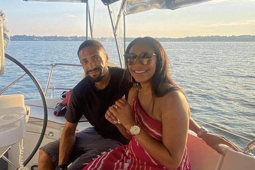 Two people on a boat with water and a distant shoreline in the background. 2