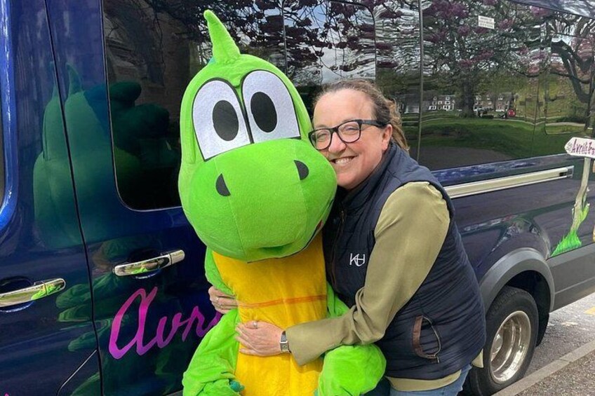En person som kramar en grön dinosauriemaskot. 3