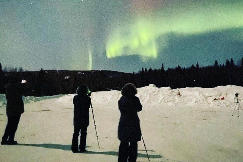 People observing the Northern Lights in a snowy landscape. 3