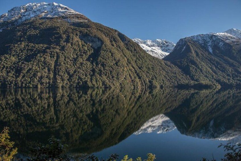 A mountain range with snow-capped peaks and a lake reflecting the scenery. 5
