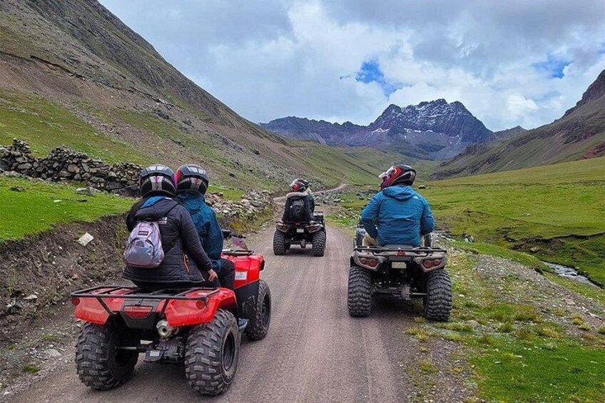Cuatro personas en vehículos todo terreno circulando por un camino estrecho, rodeado de montañas y vegetación. 2