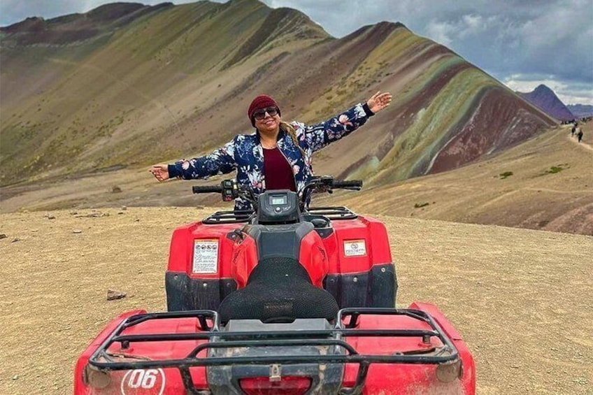 Una persona su un ATV rosso in un paesaggio arido con colline. 1