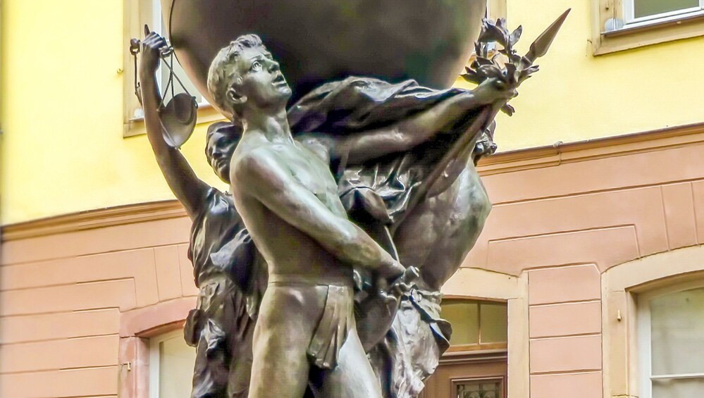 A bronze statue of a man holding scales and a sword, with another figure behind him. 4