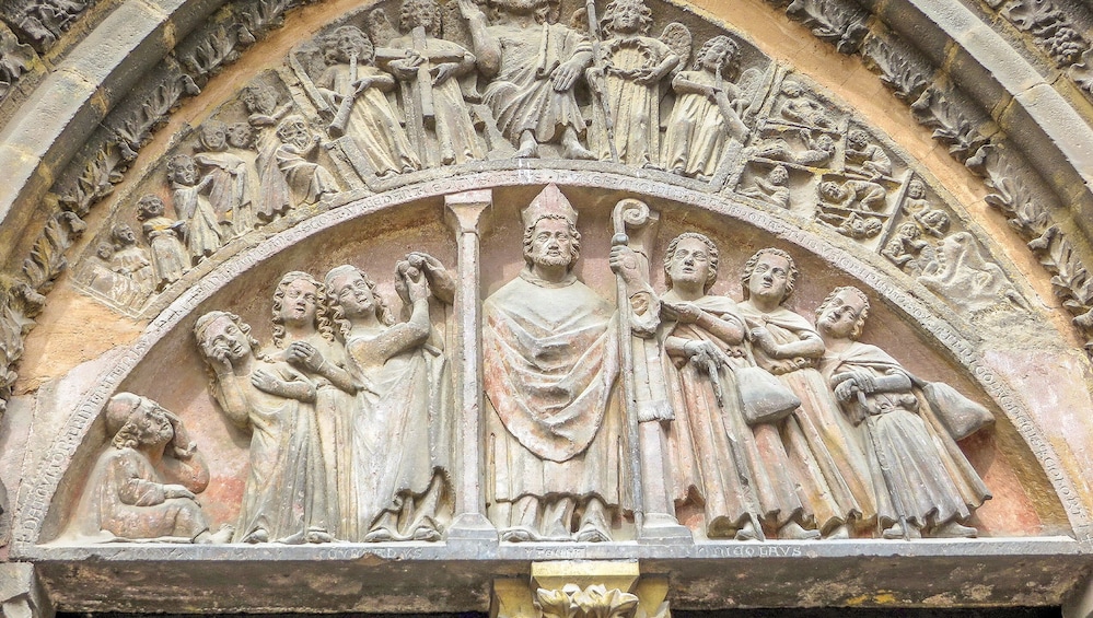 A detailed stone carving of a religious scene with multiple figures, including a central figure holding a staff. 5