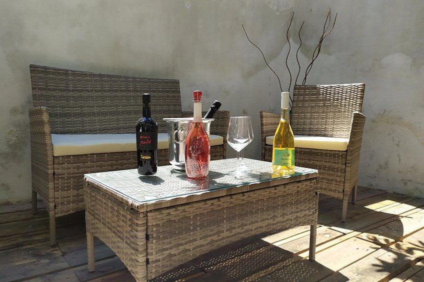 Une table en osier avec des bouteilles et des verres, un banc en osier et un mur en arrière-plan. 5