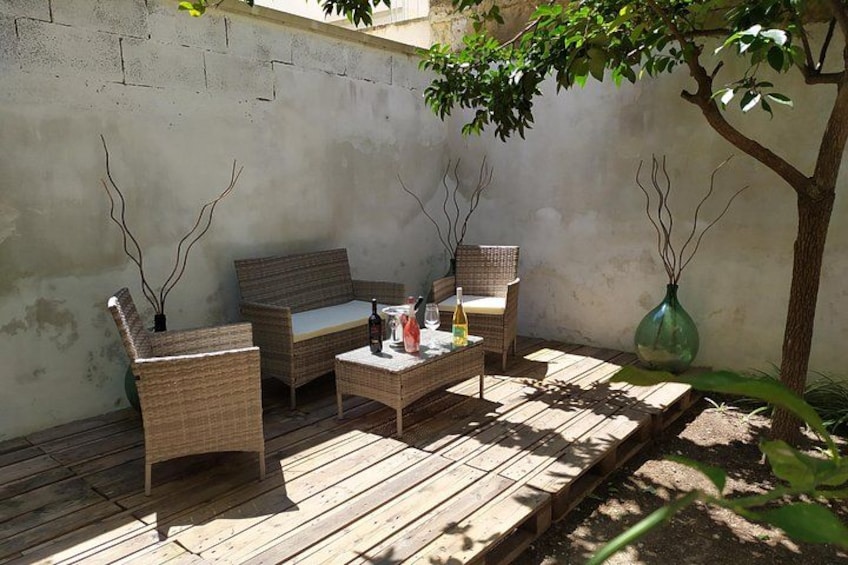 Une terrasse extérieure aménagée avec des meubles en osier, une table et des vases décoratifs. 4