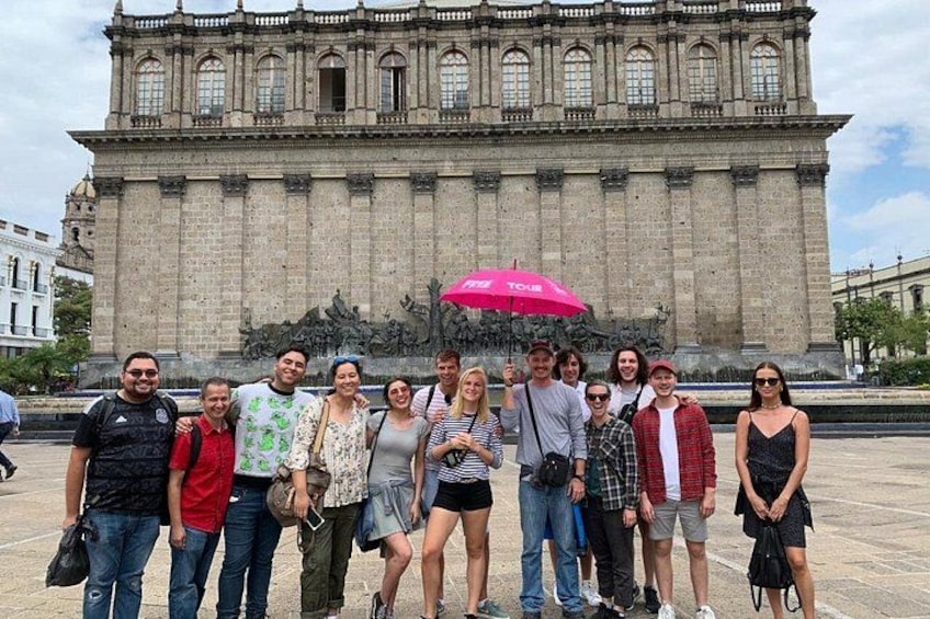 Un grupo de personas frente a un edificio histórico grande con columnas y estatuas. 4