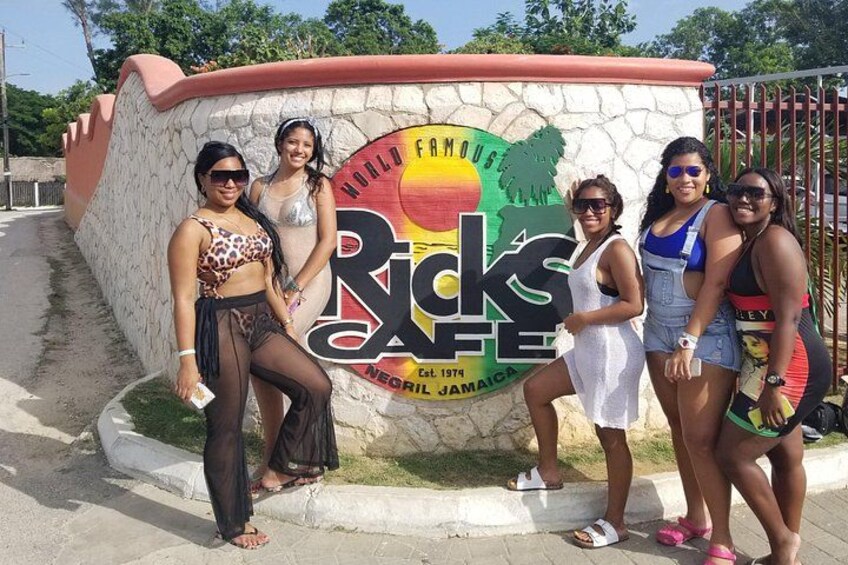 A group of people posing in front of a sign for Ricks Cafe. 5