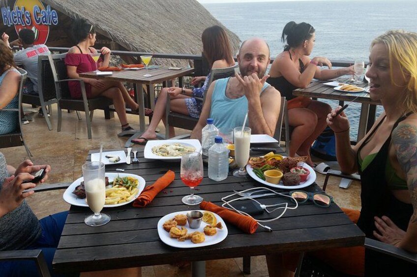 People dining at an outdoor restaurant with a view of the sea. 2