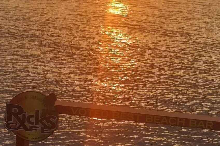 Schild einer Strandbar mit Sonnenuntergang im Wasser. 3
