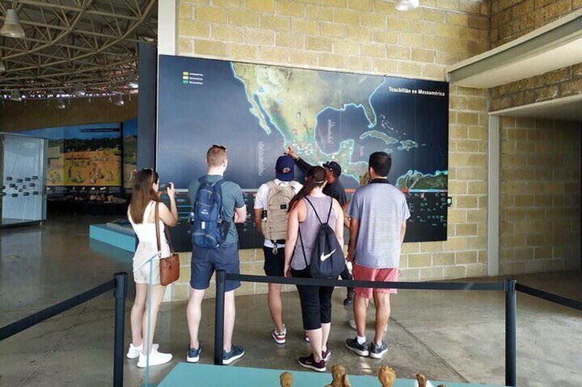 A group of people standing in front of a large map display in an indoor setting. 4