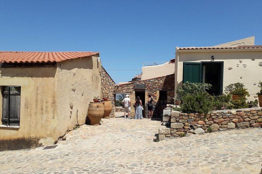 Una calle adoquinada con edificios tradicionales, muros de piedra y grandes macetas de barro. 1