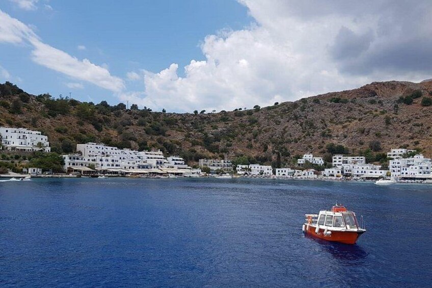 A coastal town with white buildings, a red boat on the water, and a hilly backdrop. 3