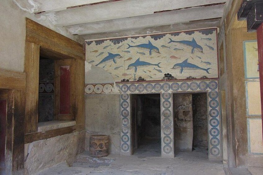 Una habitación con un mural de delfines, una chimenea con azulejos y una puerta de madera. 2